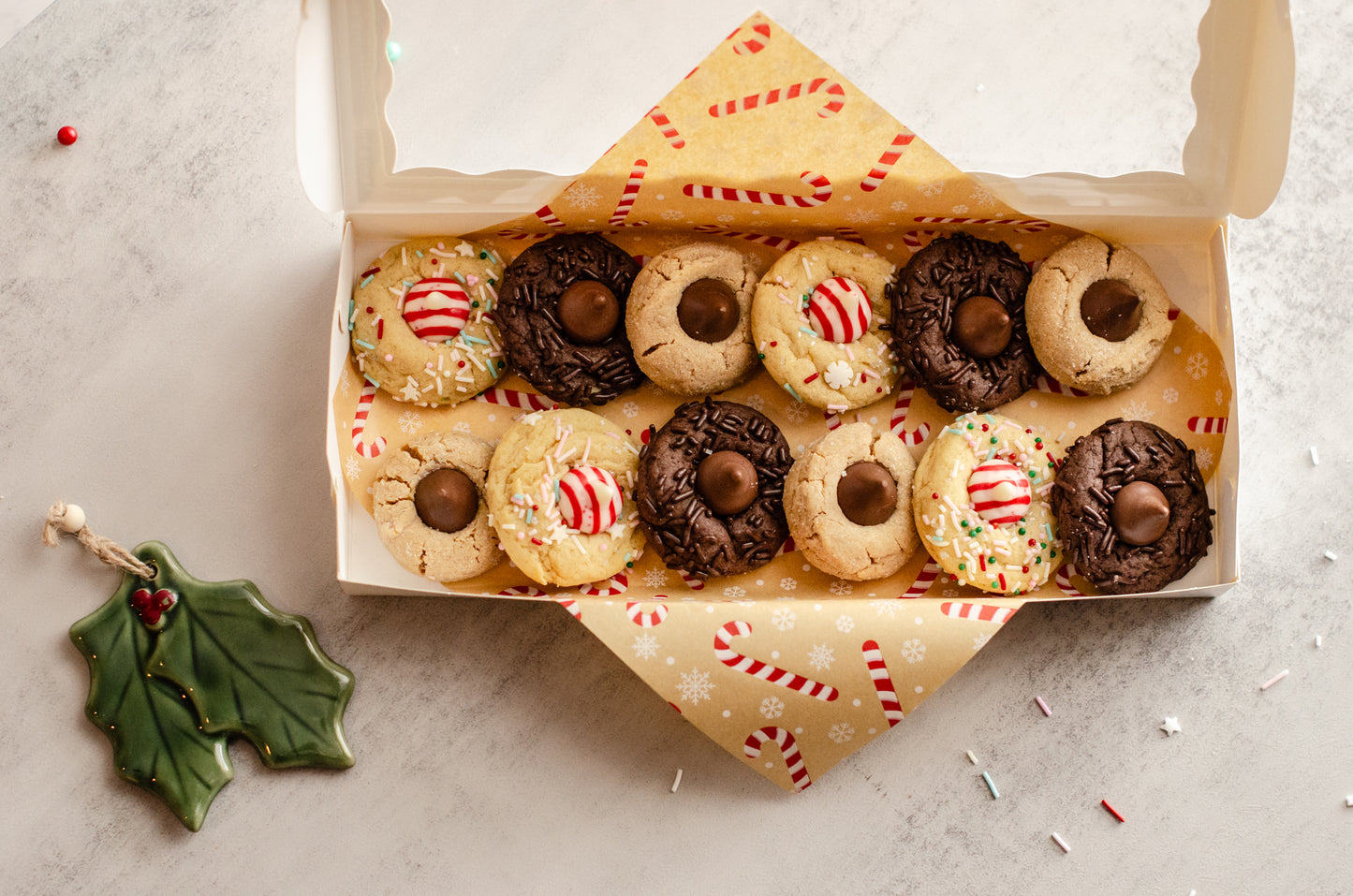 Box of assorted Holiday Blossom Cookies with a decorative candy cane paper lining on a light background, baked fresh by Chillable Bake Shop in Darien, Wisconsin.