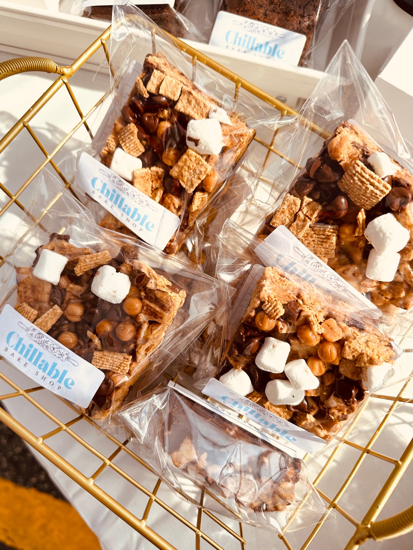 S’mores Rice Krispie treats topped with chocolate and marshmallows in clear packaging in a gold wire container at the local farmers market, fresh-made in Darien, Wisconsin.