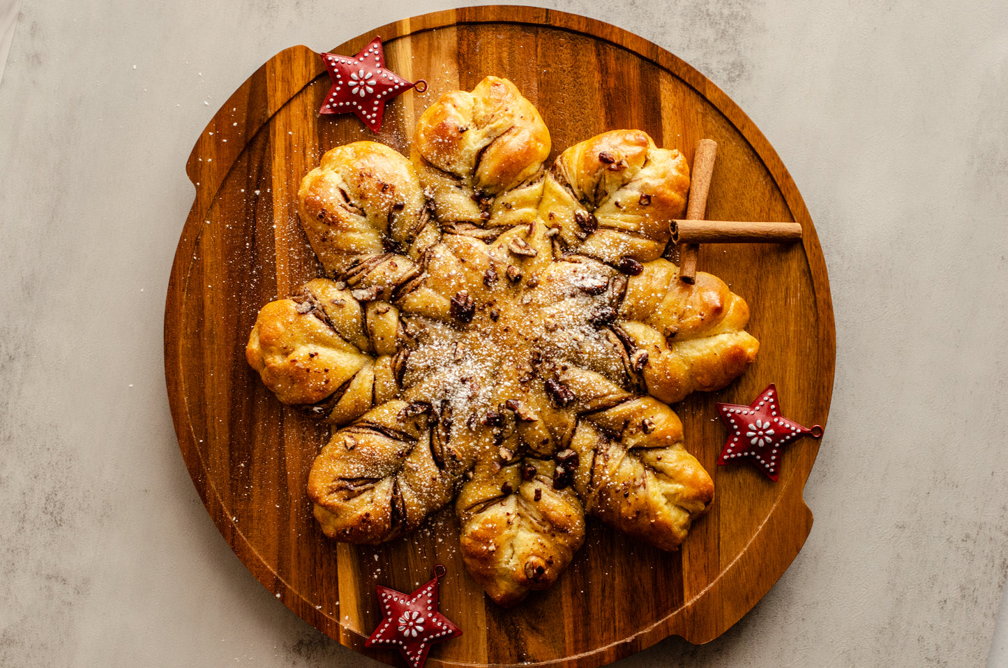 Baked chocolate pecan snowflake bread topped with powdered sugar on a wooden board with star decorations, baked fresh for the holidays by Chillable Bake Shop in Darien, WI.