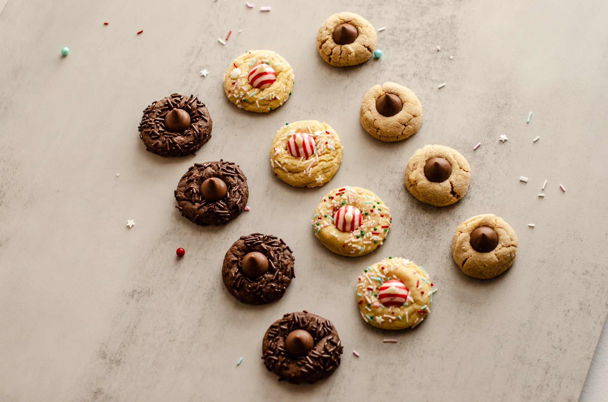 Assorted Holiday Blossom Cookies with chocolate kisses and candy decorations on a textured surface, baked fresh in Darien, WI by Chillable Bake Shop.