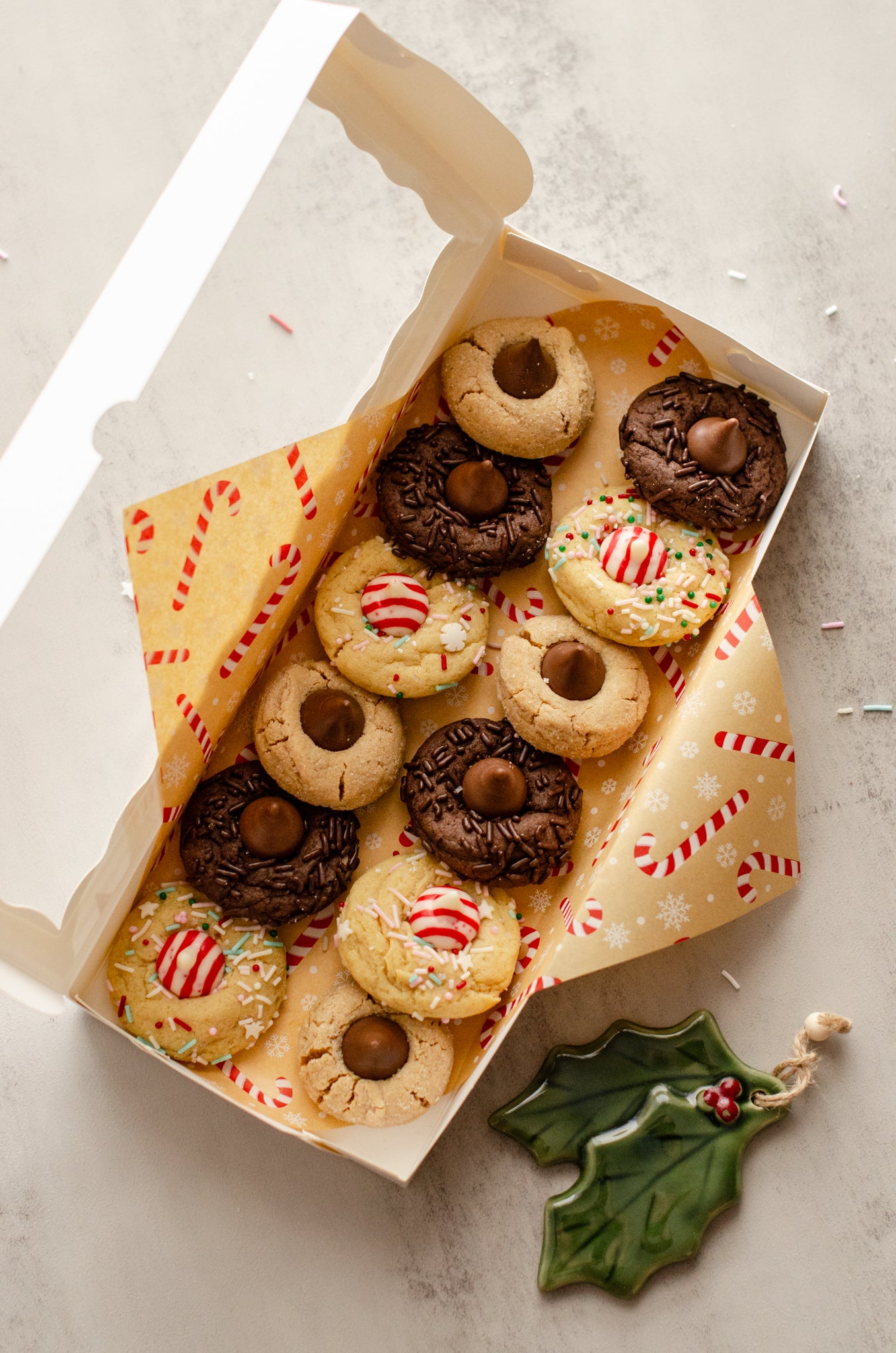 Box of assorted Holiday Blossom Cookies with a decorative candy cane paper lining on a light background, baked fresh by Chillable Bake Shop in Darien, Wisconsin.