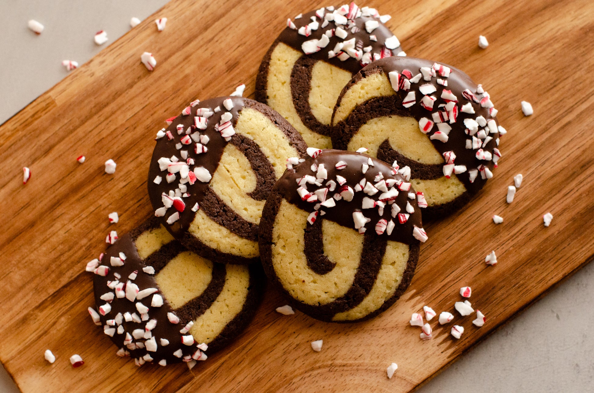 Decorative red and white peppermint pinwheel cookies arranged on a wooden tray, fresh from Chillable Bake Shop in Darien, Wisconsin.