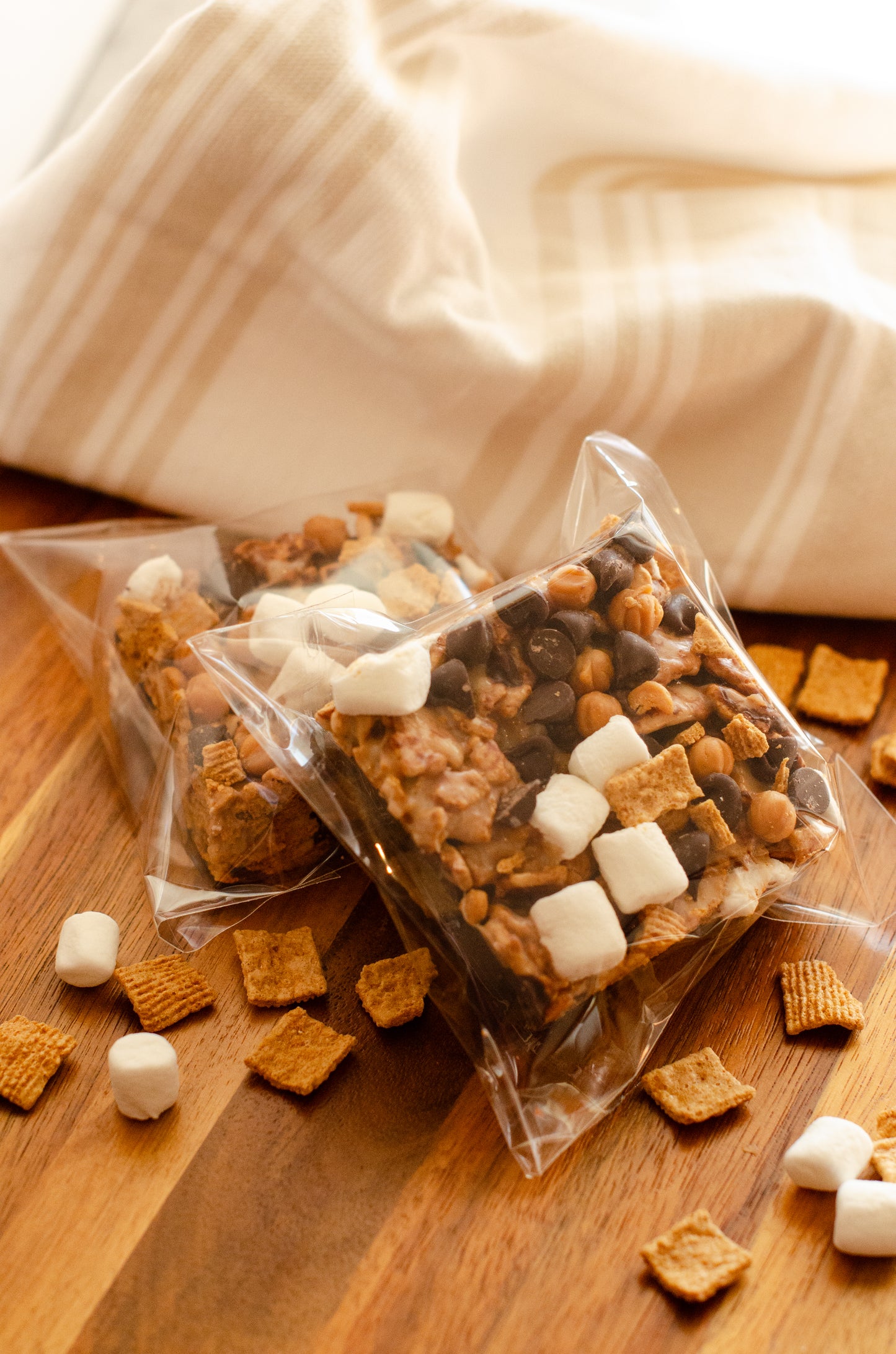 S’mores Rice Krispie treats topped with chocolate and marshmallows in clear packaging on a wooden surface, fresh-made in Darien, Wisconsin.